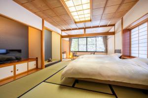 a bedroom with a large bed and a tv at ShirabuOnsen Higashiya in Yonezawa