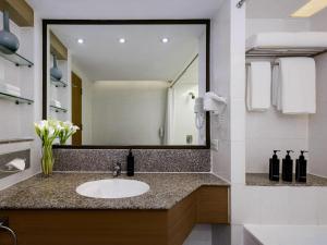 a bathroom with a sink and a large mirror at Grand Mercure Bangkok Atrium in Bangkok