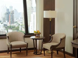 two chairs and a table in a room with a window at Grand Mercure Bangkok Atrium in Bangkok