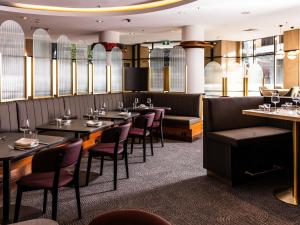 um restaurante com mesas, cadeiras e janelas em Mantra 2 Bond Street em Sidney