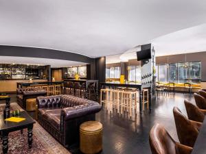 a living room with leather furniture and a bar at Mantra on Little Bourke Melbourne in Melbourne