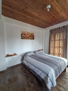 un letto in una camera da letto con soffitto in legno di Cabaña BellaVista a Oxapampa