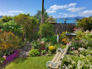 a bench sitting in a garden with flowers at Te Kouma Sunsets in Coromandel Town