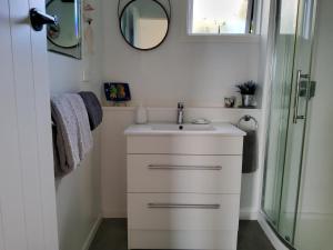 a bathroom with a sink and a shower at Te Kouma Sunsets in Coromandel Town +11 photos