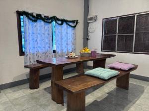 een houten tafel en bank met een schaal fruit erop bij Baboo Guesthouse in Chiang Dao