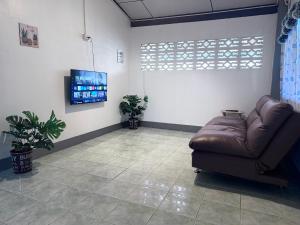 een wachtkamer met een leren bank en een flatscreen-tv bij Baboo Guesthouse in Chiang Dao