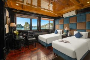 two beds in a room with a table and chairs at Beka Cruise in Cat Ba