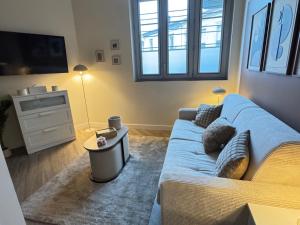 a living room with a blue couch and a tv at Marianne l'Essentiel in Bergerac