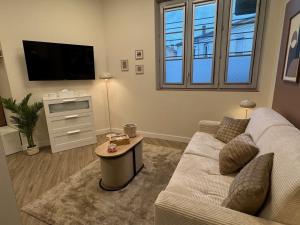 a living room with a couch and a tv at Marianne l'Essentiel in Bergerac