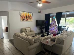 ein Wohnzimmer mit zwei Sofas und einem Weihnachtsbaum in der Unterkunft Paradise in the forest in Lehigh Acres
