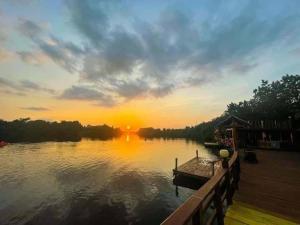 a sunset over a lake with a boat on a dock at Chi Phat River lodge in Chi Phat +3 photos