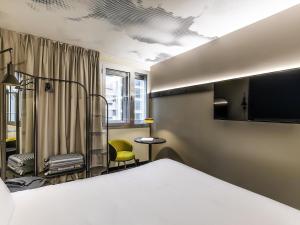 een hotelkamer met een bed en een stoel bij ibis Saint Paul Trois Chateaux in Saint-Paul-Trois-Châteaux