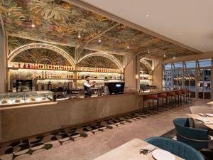 Un restaurante con un bar con techo floral. en Mövenpick Hotel Jakarta City Centre, en Yakarta