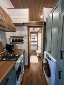 Tiny Rustic at Yosemite Gateway في غروفلاند: مطبخ مع موقد وغسالة ومجفف