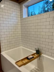 Tiny Rustic at Yosemite Gateway في غروفلاند: حمام مع حوض استحمام مع نافذة