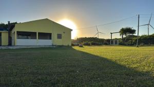 un edificio giallo con il sole che tramonta dietro di esso di Recanto Sherek a Rio Grande