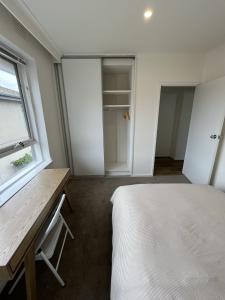a bedroom with a bed and a desk and a window at Private Cozy Room in a Spacious Flat in Carnegie in Carnegie