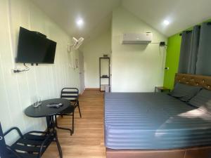 a room with a bed and a table and a tv at รักกันต์ รีสอร์ท in Ban Sakat Namman