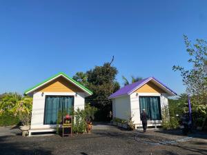 two small cottages with a person standing in front of them at รักกันต์ รีสอร์ท in Ban Sakat Namman