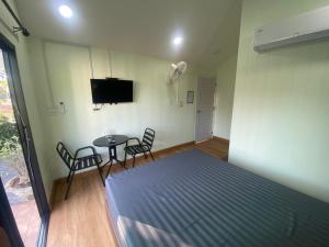 a bedroom with a bed and a table and chairs at รักกันต์ รีสอร์ท in Ban Sakat Namman