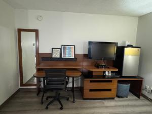 a desk with a computer and a monitor and a chair at Canadas Best Value Inn Kelowna in Kelowna
