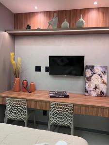 einen Schreibtisch mit einem TV an der Wand mit Stühlen in der Unterkunft Rooftop com vista para o mar in Fortaleza