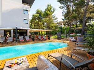 - une piscine sur une terrasse avec des chaises et un bâtiment dans l'établissement Mercure Aix-en-Provence La Duranne Gare TGV, à Aix-en-Provence