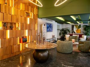 a lobby with a table and chairs in a room at Mercure Larnaca Finikoudes Beach in Larnaka