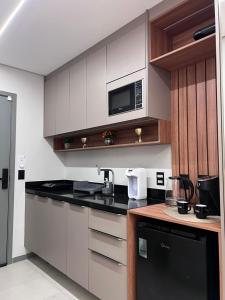 eine Küche mit weißen Schränken und einer schwarzen Arbeitsplatte in der Unterkunft Rooftop com vista para o mar in Fortaleza