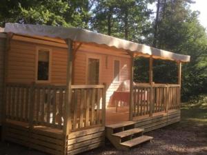 eine kleine Holzhütte mit einer Veranda und einer Treppe in der Unterkunft Mobil-home confortable avec terrasse à Saint-Gérons - API-1-52-1315 in Saint-Étienne-Cantalès + 11 Fotos