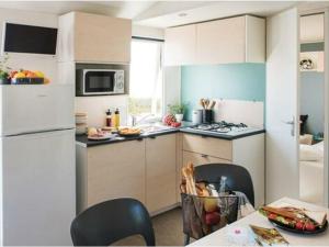 eine Küche mit weißen Schränken und einem weißen Kühlschrank in der Unterkunft Mobil-home confortable avec terrasse à Saint-Gérons - API-1-52-1315 in Saint-Étienne-Cantalès