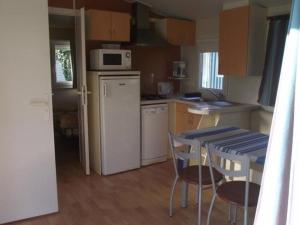 a kitchen with a white refrigerator and a table and chairs at Mobil-home confortable avec terrasse à La Couarde - API-1-52-1305 in Saint-Nicolas des Eaux +7 photos