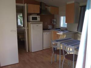 a kitchen with a white refrigerator and a table and chairs at Mobil-home confortable avec terrasse à La Couarde - API-1-52-1305 in Saint-Nicolas des Eaux