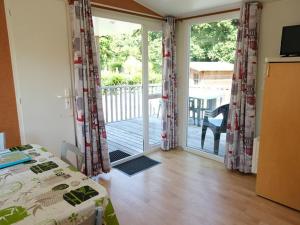 a bedroom with a bed and a sliding glass door at Mobil-home confortable avec terrasse à La Couarde - API-1-52-1305 in Saint-Nicolas des Eaux