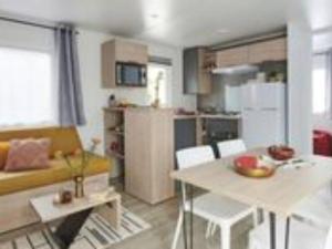 eine Küche und ein Wohnzimmer mit Tisch und Stühlen in der Unterkunft Mobil-home 35m² avec Terrasse - Saint-Gérons - API-1-52-1314 in Saint-Étienne-Cantalès + 7 Fotos