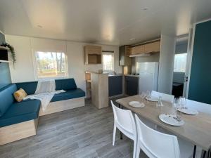 eine Küche und ein Wohnzimmer mit einem Tisch und einem blauen Sofa in der Unterkunft Mobil-home 35m² avec Terrasse - Saint-Gérons - API-1-52-1314 in Saint-Étienne-Cantalès
