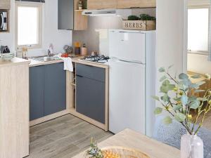 eine Küche mit einem weißen Kühlschrank und einem Tisch in der Unterkunft Mobil-home 35m² avec Terrasse - Saint-Gérons - API-1-52-1314 in Saint-Étienne-Cantalès