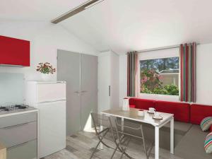 eine Küche und ein Wohnzimmer mit einem roten Sofa und einem Tisch in der Unterkunft Mobil-home 27m² à Saint-Gérons avec terrasse - API-1-52-1316 in Saint-Étienne-Cantalès