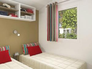 ein Schlafzimmer mit zwei Betten und einem Fenster in der Unterkunft Mobil-home 27m² à Saint-Gérons avec terrasse - API-1-52-1316 in Saint-Étienne-Cantalès