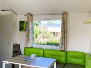 ein grünes Sofa in einem Zimmer mit einem Fenster in der Unterkunft Mobil-home 27m² à Saint-Gérons avec terrasse - API-1-52-1316 in Saint-Étienne-Cantalès