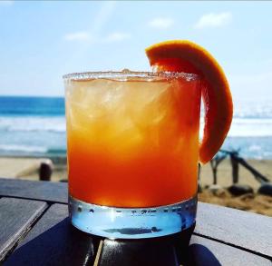 a drink with an orange peel on a table at the beach at The Cerritos Beach Inn in El Pescadero