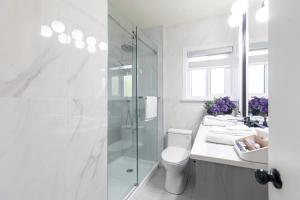 a white bathroom with a shower and a toilet at Vancouver Cozy Cove in Vancouver +47 photos