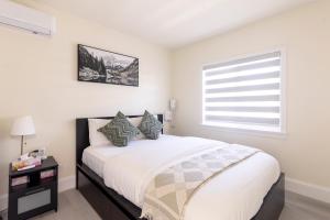 a white bedroom with a bed with pillows and a window at Vancouver Cozy Cove in Vancouver