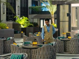 a man standing in a restaurant with tables and chairs at Fairmont Mumbai in Mumbai +220 photos