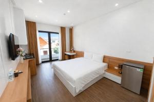 a bedroom with a white bed and a television at TD Apartment in Hai Phong