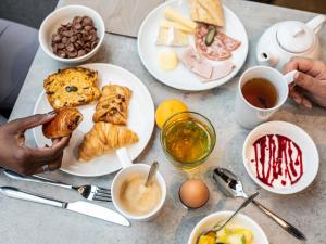 a table with plates of breakfast foods and coffee at ibis Styles Colombes Paris Ouest (Ouverture Octobre 2025) in Colombes