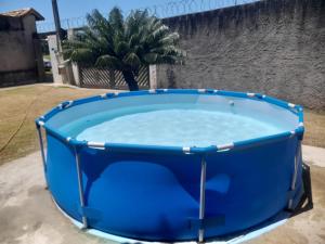 ein großer blauer Pool mit einer Palme im Hintergrund in der Unterkunft Peruíbe - Oasis - Casa espaçosa, lugar tranquilo in Peruíbe