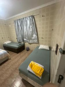 ein kleines Zimmer mit zwei Betten und einem Fenster in der Unterkunft Pousada próximo ao hospital regional in São José
