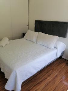 Bett mit weißer Bettwäsche und grauem Kopfteil in der Unterkunft Departamento vacacional in Arica