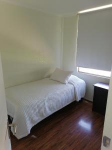 ein kleines weißes Bett in einem Zimmer mit Fenster in der Unterkunft Departamento vacacional in Arica
